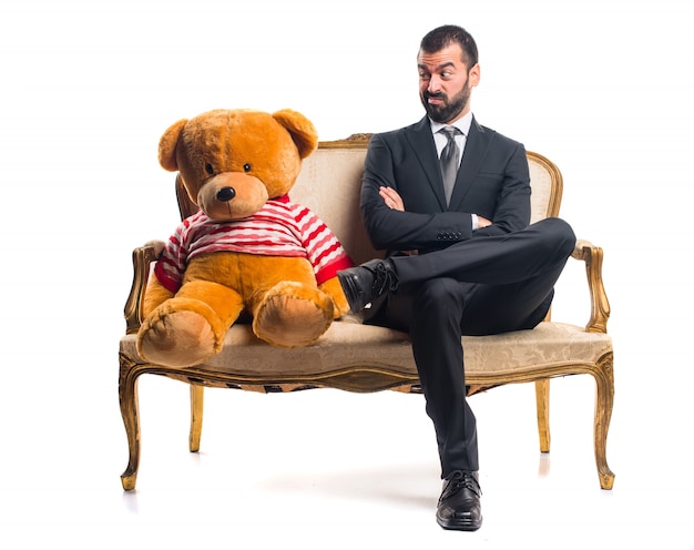 Free photo businessman with teddy sitting on vintage armchair