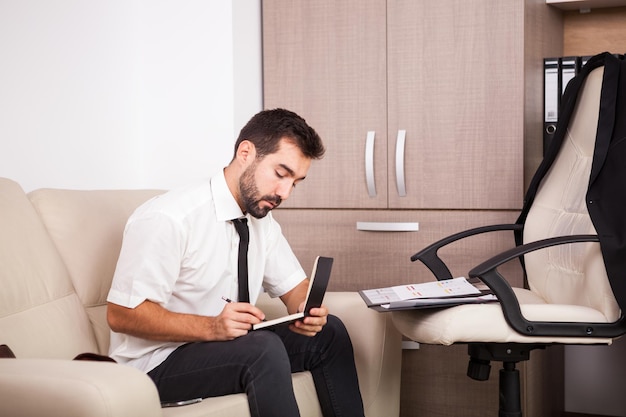 Businessman working in the office on the couch putting long hours of work. Businessperson in professional environment