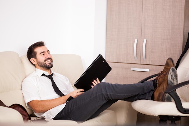 Businessman working in the office on the couch putting long hours of work. Businessperson in professional environment