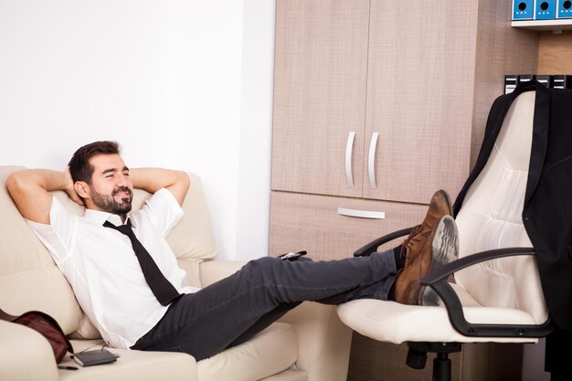 Businessman working in the office on the couch putting long hours of work. Businessperson in professional environment