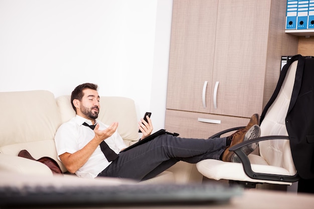 Foto gratuita uomo d'affari che lavora in ufficio sul divano mettendo lunghe ore di lavoro. imprenditore in ambiente professionale