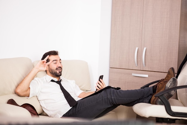 Businessman working in the office on the couch putting long hours of work. Businessperson in professional environment