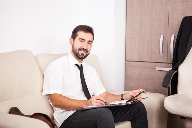 Businessman working in the office on the couch putting long hours of work. Businessperson in professional environment