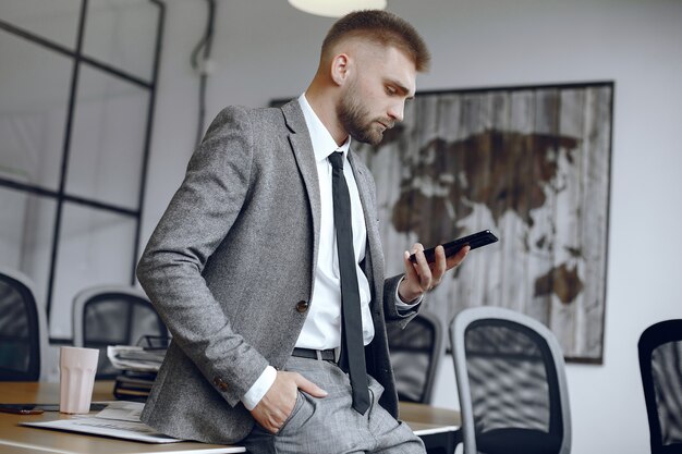 オフィスで働くビジネスマン。男性は電話を使用します。男はオフィスに座っています