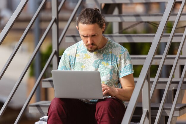 Businessman working outdoors with laptop, looking on computer screen