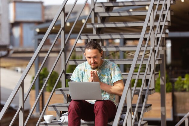 Бизнесмен работает на открытом воздухе с ноутбуком, глядя на экран компьютера