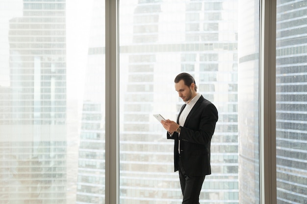 Businessman working on tablet near large window