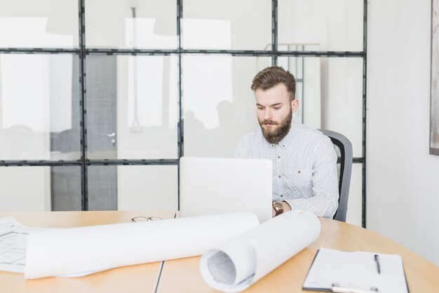 Foto gratuita uomo d'affari che lavora con il computer portatile in ufficio