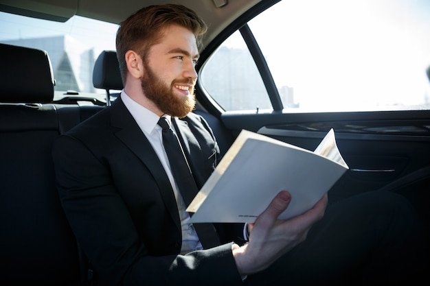 Businessman working with papers in the back seat