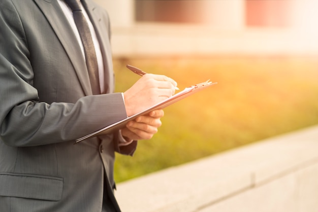 Businessman writing on clipboard