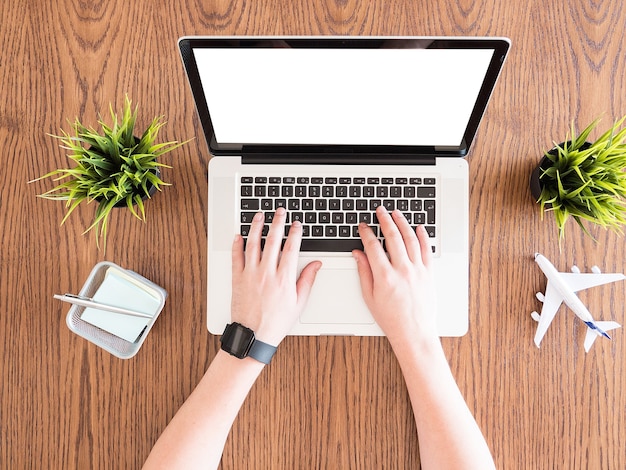 Businessman writing on his laptop concept image on woden desk,travel , pot of grass, notes