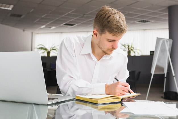 Businessman writing schedule in diary