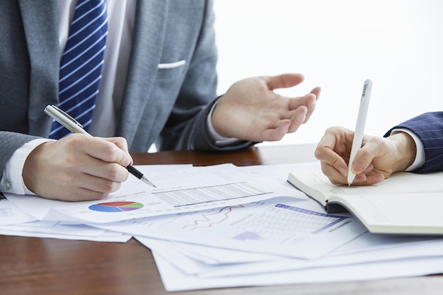 Businessmen in elegant suits at a business meeting taking notes in the office