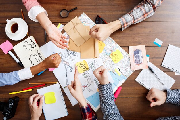  businessmen hands on wooden table with documents and drafts