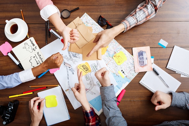  businessmen hands on wooden table with documents and drafts