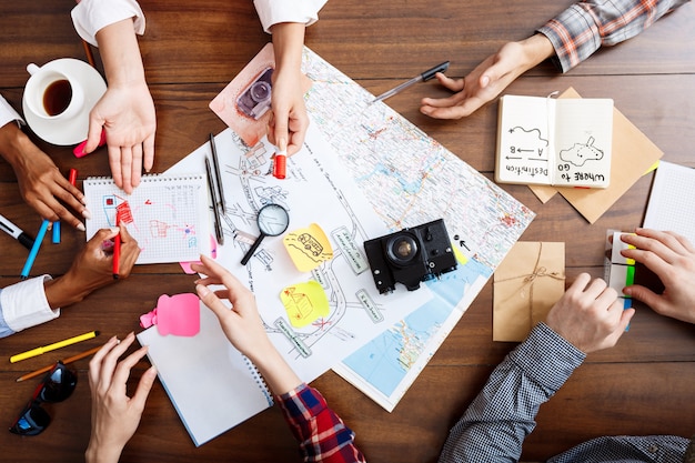  businessmen hands on wooden table with documents and drafts