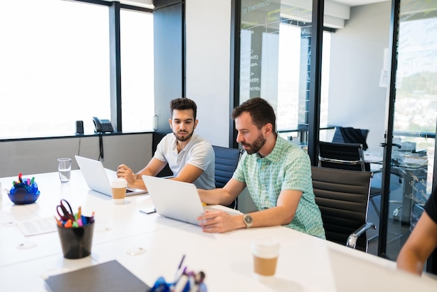 Businessmen using laptop while sitting at desk in office