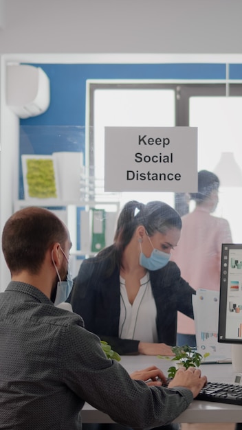 Businesspeople analysing financial graphics while working after lockdown in new business office wearing protective face mask to prevent infection with coronavirus