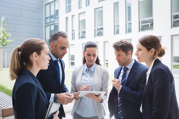 Businesspeople discussing over digital tablet