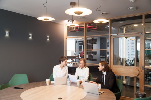 Businesspeople having discussion at team meeting in modern office interior