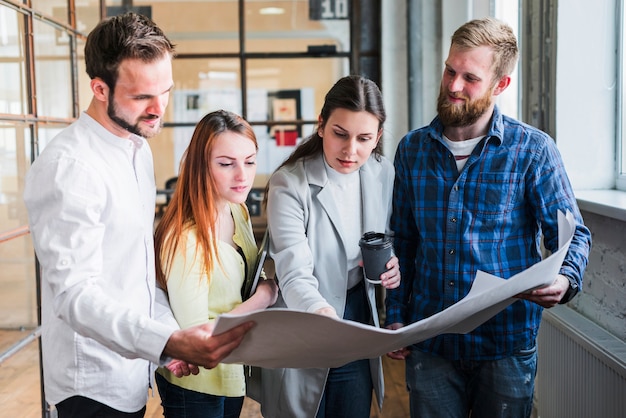 Businesspeople looking at blue print and discussing something