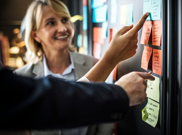 Businesspeople planning tasks with sticky notes