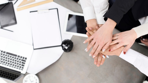 Businesspeople stacking each other's hand over the desk