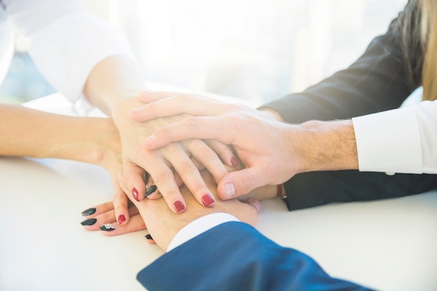 Businesspeople stacking each other's hand on white desk