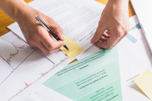 Businessperson's hand marking tick on sticky notes over document