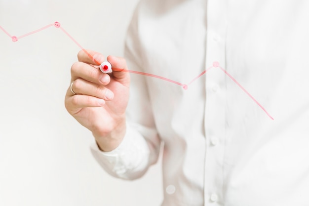 Businessperson's hand preparing red graph on glass board