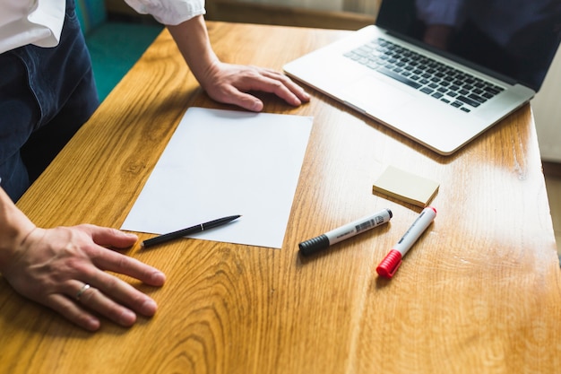 Free photo businessperson's hand with blank white paper over wooden desk