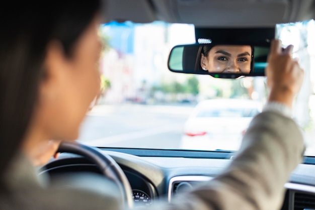 Деловая женщина, регулирующая ее автомобильное зеркало заднего вида