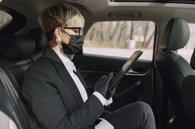 車の中に座っている黒いマスクの女性実業家