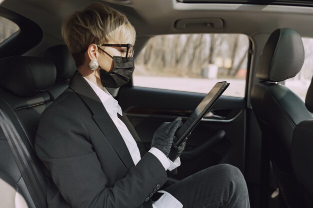 Businesswoman in a black mask sitting inside a car