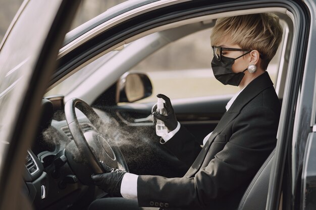 Businesswoman in a black mask sitting inside a car