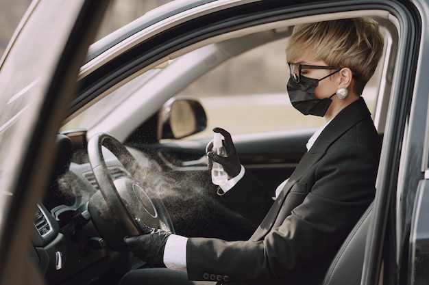 Businesswoman in a black mask sitting inside a car