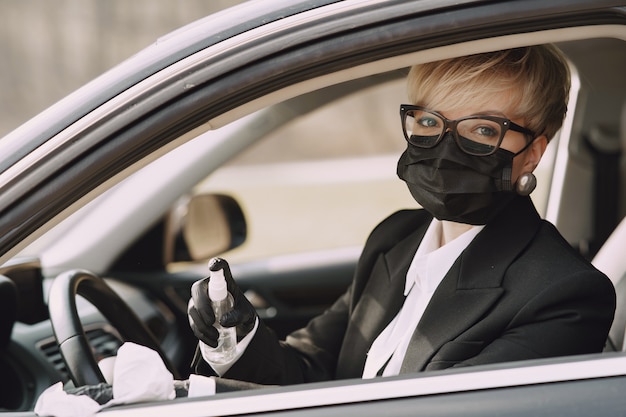 Foto gratuita donna di affari in una maschera nera che si siede dentro un'automobile