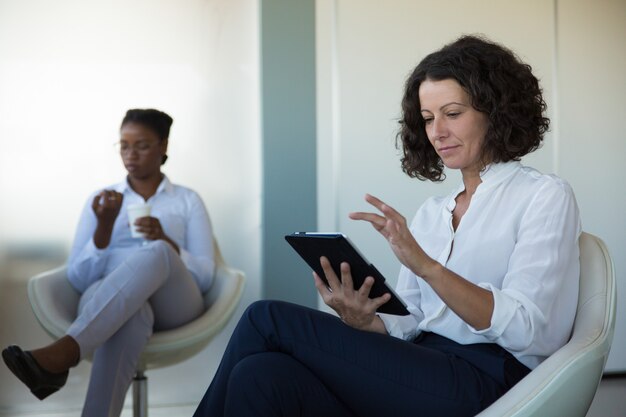 Businesswoman browsing pages on tablet in office lounge