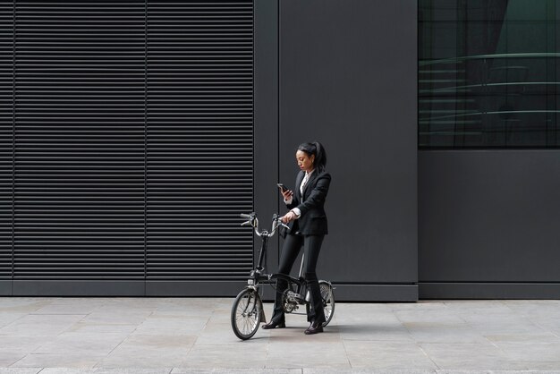 Businesswoman checking smartphone on a bike