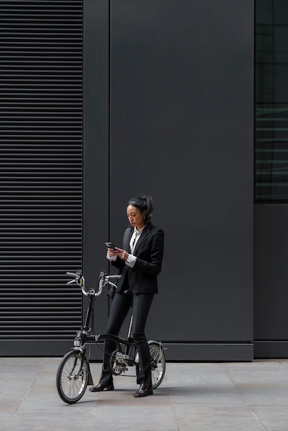 Donna di affari che controlla smartphone su una bici