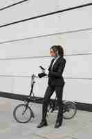 Free photo businesswoman checking smartphone with a bike