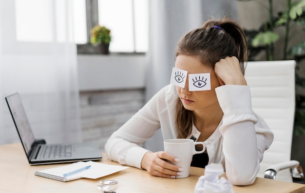 Free photo businesswoman covering her eyes with drawn eyes on paper