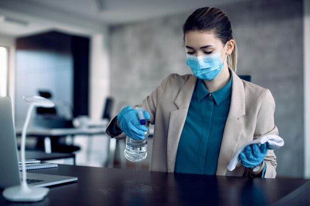 Businesswoman disinfecting her office desk during COVID19 pandemic