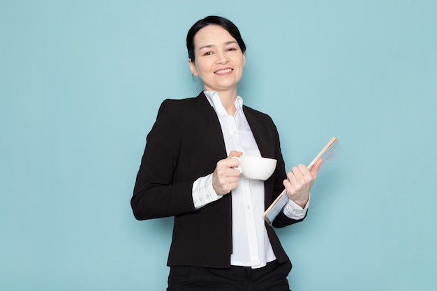 Businesswoman drinking coffee and holding magazine