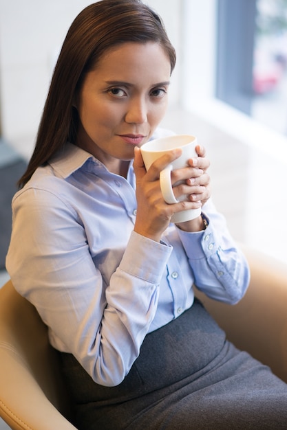 謎笑顔でお茶を飲む女性実業家