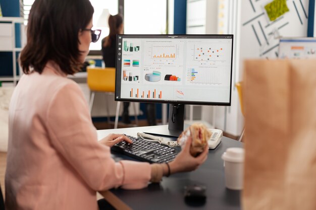 Businesswoman eating tasty sandwich having meal break working in business company