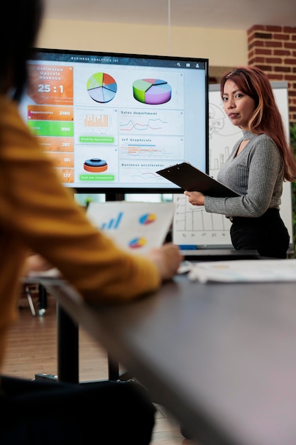 Businesswoman explaining management statistics to asian manager working together at company strategy during business meeting in startup office. Businesswoman planning partnership project