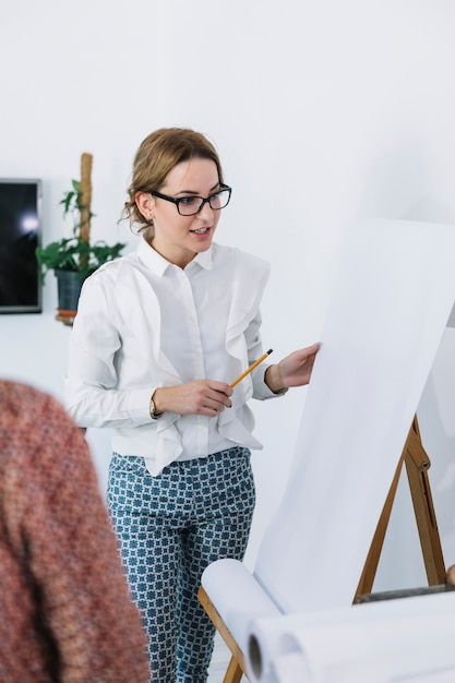 Foto gratuita donna di affari che spiega nuovo piano aziendale su flipchart