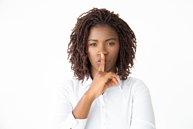 Businesswoman gesturing for silence and looking at camera