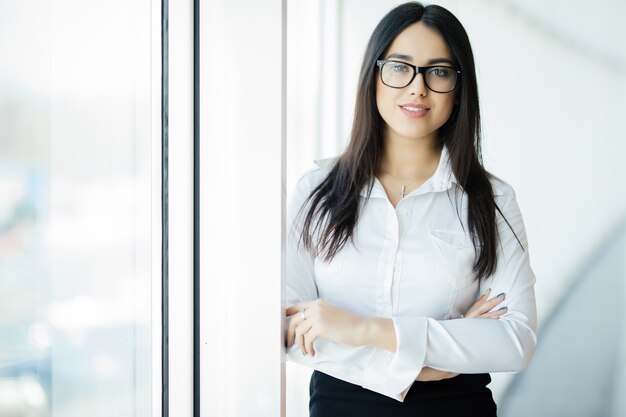 Businesswoman in glasses crossed hands portrait in office with panoramic windows. Business concept